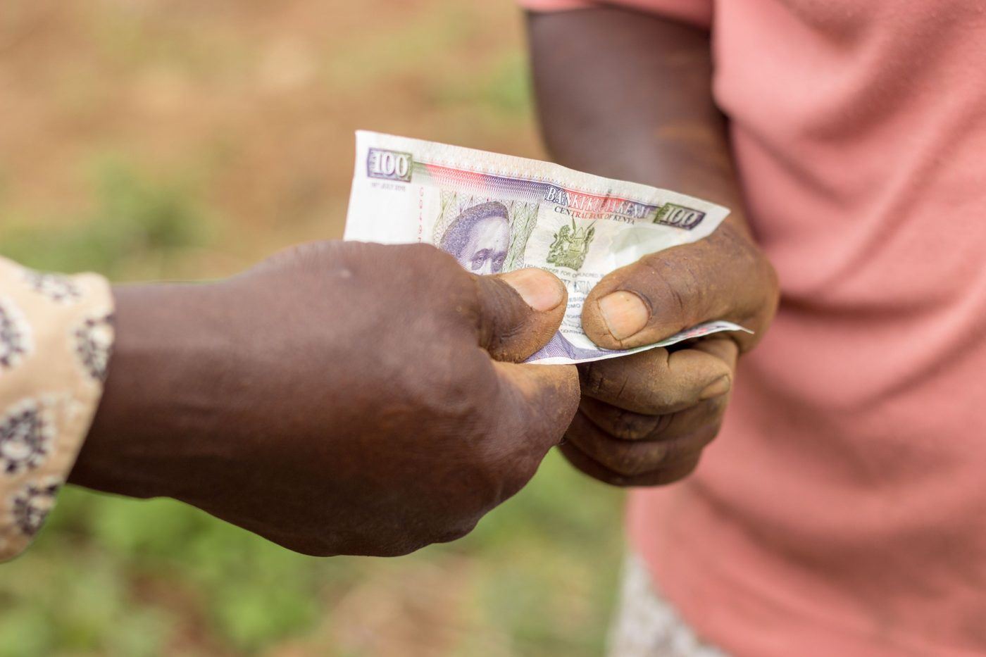 Hands exchanging Kenyan currency